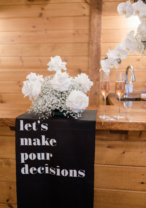 Image of Everly Champagne Flute Rentals on bar with sign "let's make pour decisions".