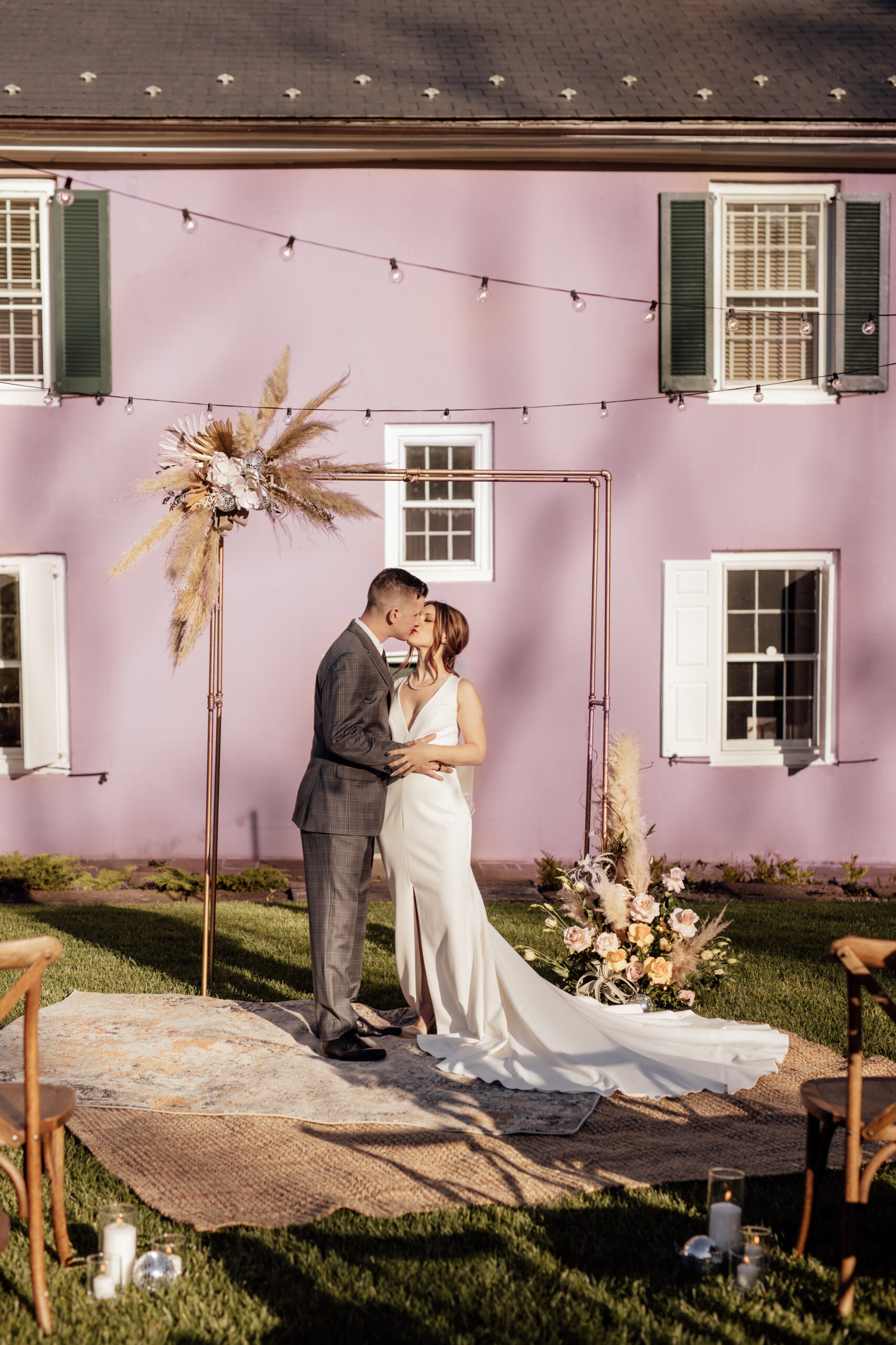 Image of bride and groom kissing in front of copper wedding arch. Also features our Colt and Jute rug rentals.