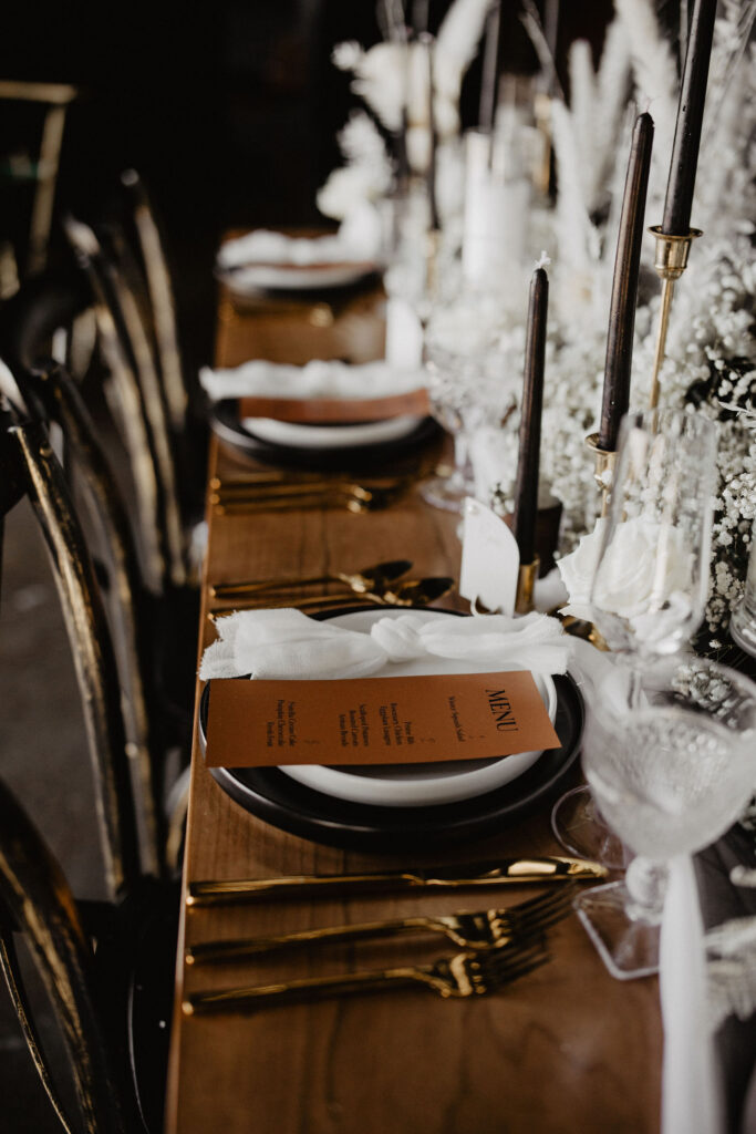 Image of tabletop place setting with black and white stoneware and primrose flatware