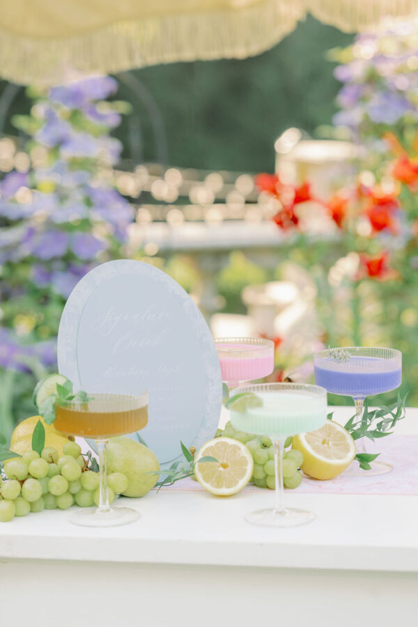image of clear champage fluted coupes with colorful drinks inside at a wedding bar