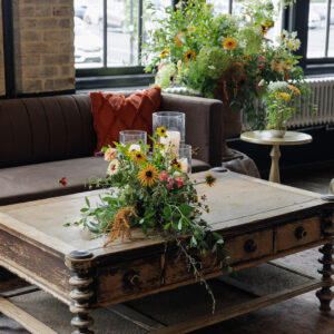 Buford coffee table staged for a comfortable conversation setting at a wedding reception. Styled with floral arrangements.