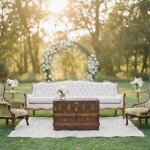 Outdoor lounge setting including Simon and Sable velvet accent chairs, off white vintage Clarice sofa, Eisnehower vintage trunk, 2 Blanche modern gold side tables, and ivory Britton rug.