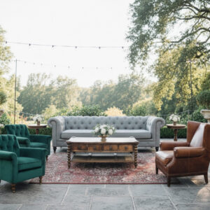 Lounge setting including a the light gray Charleston sofa, two hunter green Glenn armchairs, the brown leather Duke armchair, the wooden Beauford coffee table, two modern oak Lillian side tables, and the red Moroccan Rafael rug.