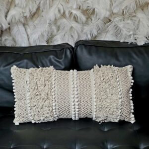 Elongated cream and white throw pillow with white accents and cream fringe.