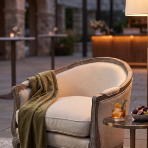AI generated photo of the Carley accent chair styled in an intimate cocktail hour setting with string lights and a side table.