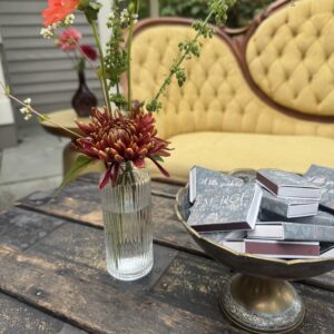 Small, glass fluted bud vase with minimal floral arrangement placed on a coffee table during an intimate party setting.